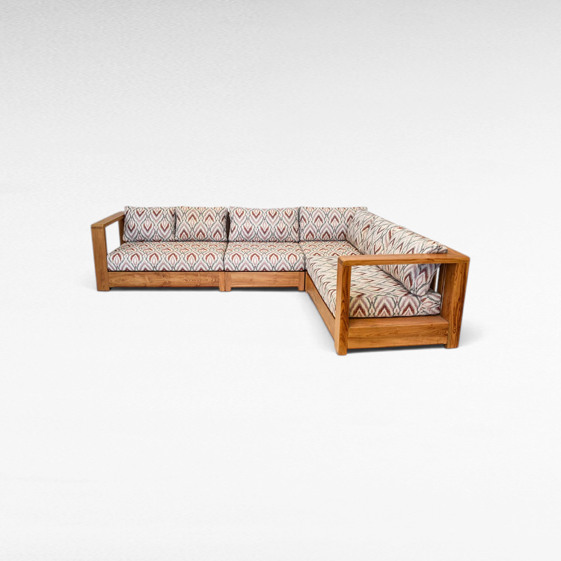Chora Barefoot Luxury Living teak wood L-shaped sectional sofa with patterned cushions in a warm natural wood finish.
