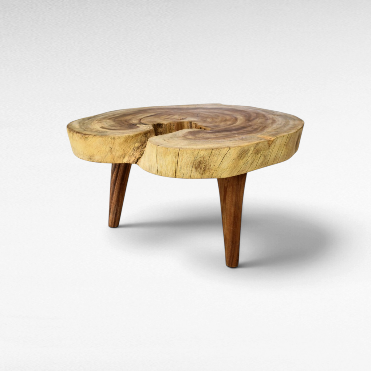 Chora Barefoot Luxury Living suar wood coffee table with a natural live edge round top and three tapered wooden legs.