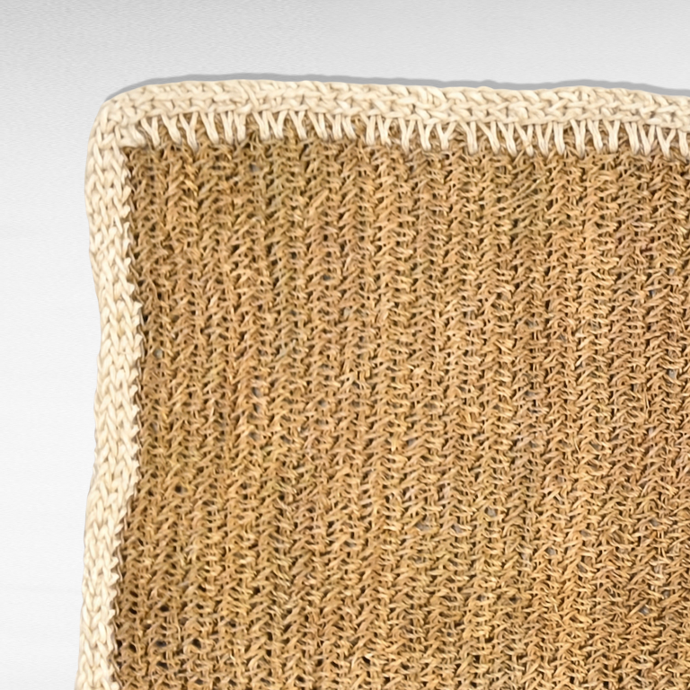 Chora Barefoot Luxury Living synthetic grass carpet with a textured natural brown weave and a white braided border.