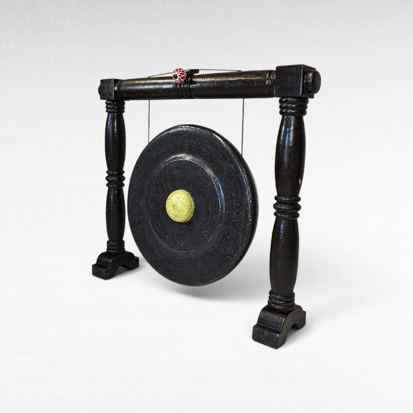 Chora Barefoot Luxury Living black ceremonial gong with a light yellow center and decorative red and white ball on top.