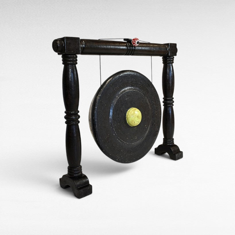 Chora Barefoot Luxury Living black ceremonial gong decoration with a yellow center and wooden stand.