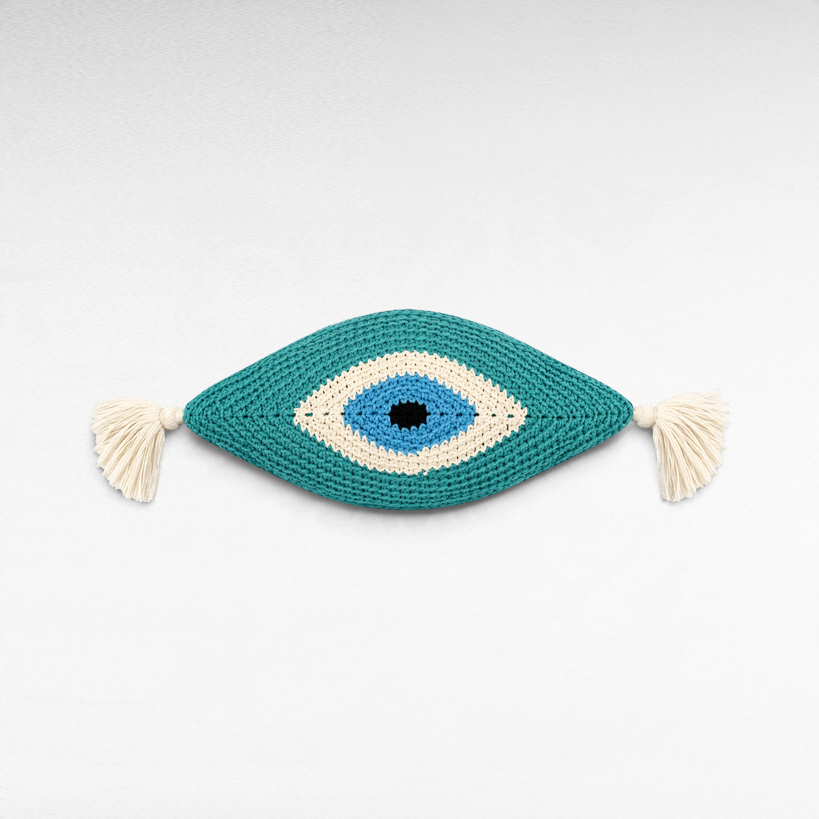 Chora Barefoot Luxury Living eye-shaped cotton pillow in teal, blue, white, and black with decorative side tassels.