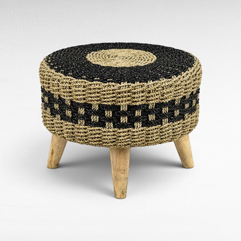 Chora Barefoot Luxury Living round stool with a black and natural hand-braided synthetic rattan seat and teak wood legs.