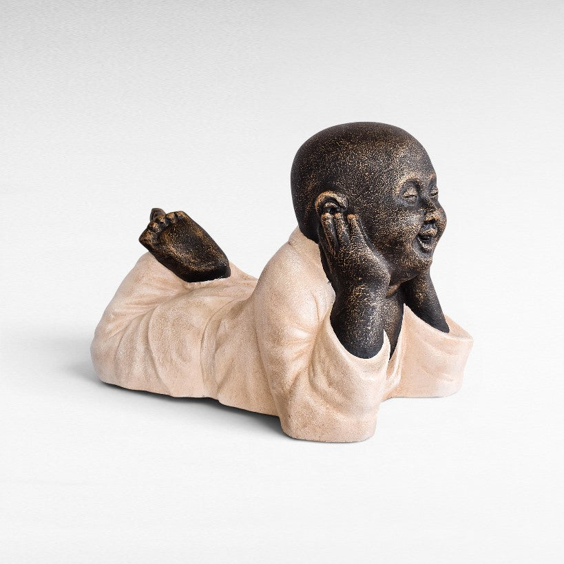 Chora Barefoot Luxury Living Figurine Shaolin, a fiber cement sculpture of a monk lying down with hands on ears.