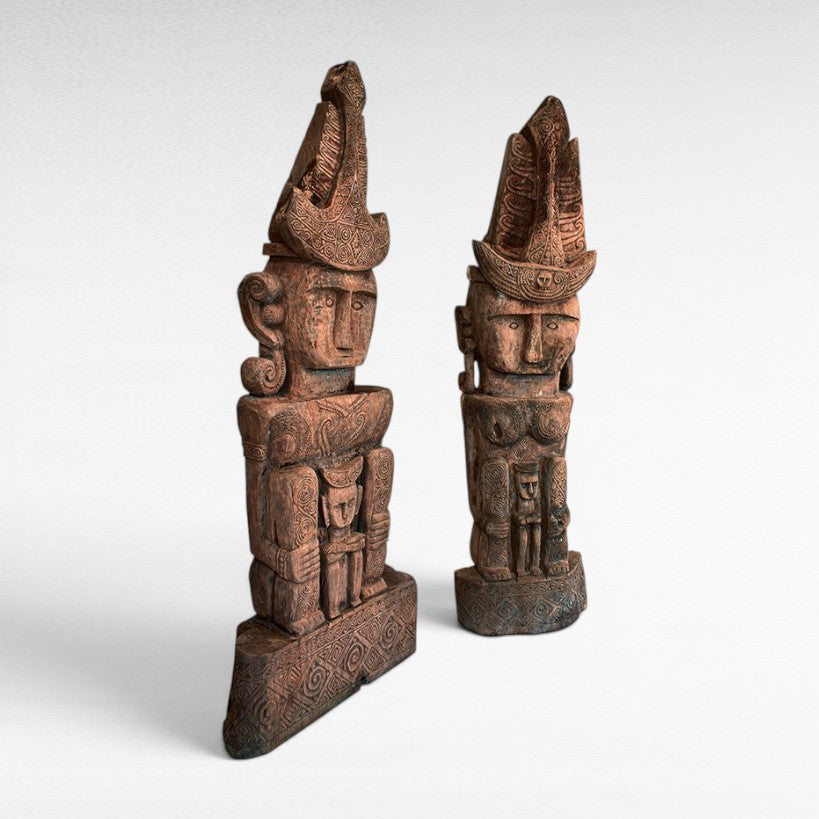 Chora Barefoot Luxury Living set of two carved teak wooden totems with intricate patterns and headdresses.