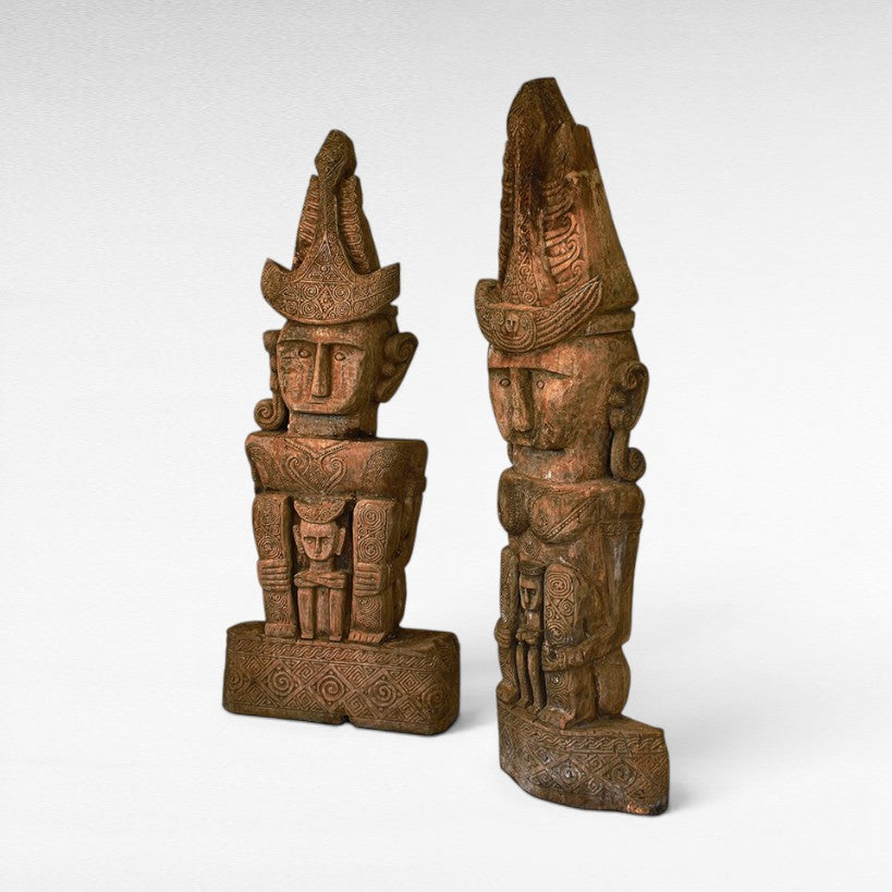 Chora Barefoot Luxury Living set of two carved teak wooden totems with intricate patterns and headdresses.