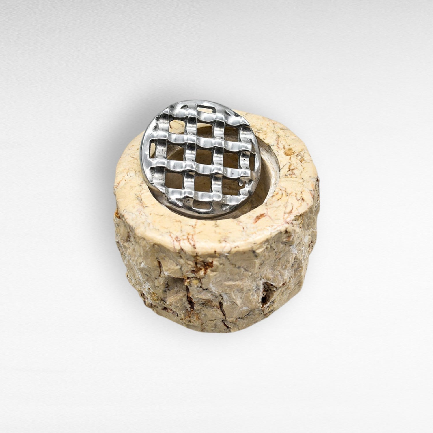 Chora Barefoot Luxury Living beige stone ashtray with a silver metal grate insert. Textured, rustic design.