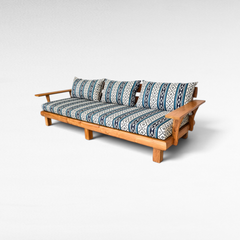 Chora Barefoot Luxury Living teak wood sofa with blue and white geometric patterned cushions on a white background