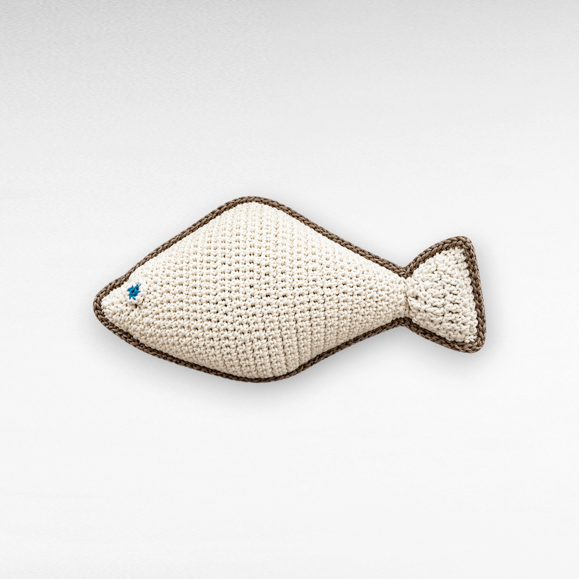 Chora Barefoot Luxury Living off-white crochet fish pillow with a brown border and a small blue embroidered eye.