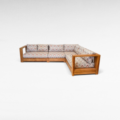 Chora Barefoot Luxury Living teak wood L-shaped sectional sofa with patterned cushions in a warm natural wood finish.