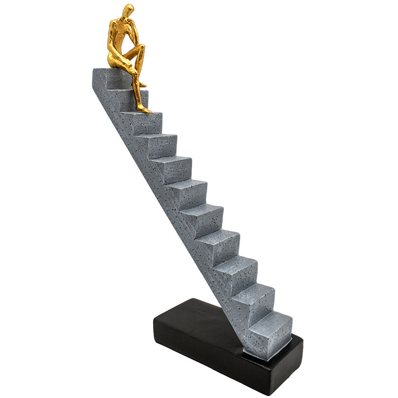 GOLD FIGURINE SITTING ON STAIR