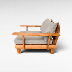 Chora Barefoot Luxury Living teak wood armchair with grey cushions, featuring a natural wood grain and armrests.