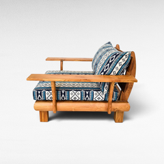 Chora Barefoot Luxury Living teak wood sofa chair with blue and white geometric patterned cushions, side view