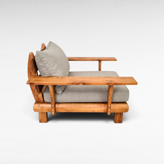 Chora Barefoot Luxury Living teak wood armchair with grey cushions, featuring a natural wood grain side profile.