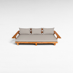 Chora Barefoot Luxury Living teak wood sofa with light grey cushions and wide armrests on a white background