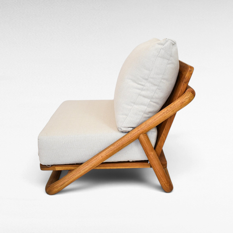 Chora Barefoot Luxury Living teak wood sofa chair with light beige fabric cushions in a side profile view.