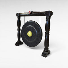 Chora Barefoot Luxury Living black ceremonial gong with a light yellow center and decorative red and white ball on top.