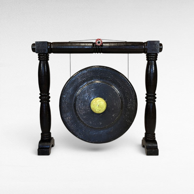 Chora Barefoot Luxury Living black ceremonial gong with a yellow mallet on a dark wooden stand.