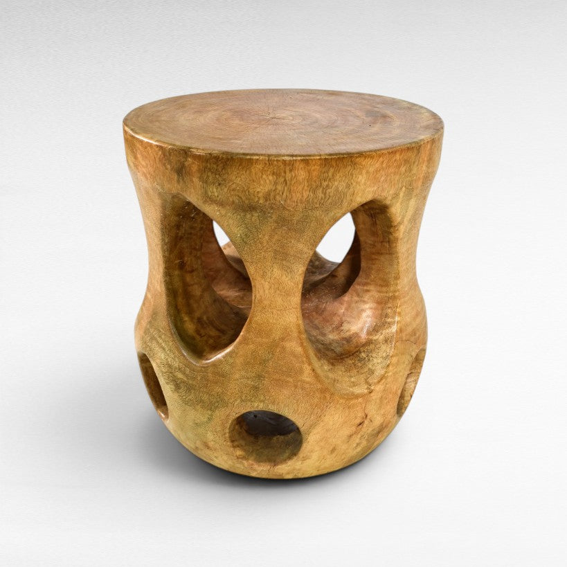 Chora Barefoot Luxury Living carved wood side table with curves and holes, natural wood finish.