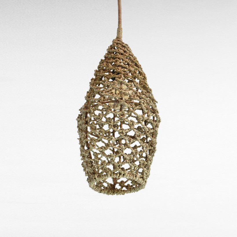 Chora Barefoot Luxury Living natural rattan pendant light with intricate weave and teardrop shape, casting a warm glow.