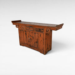 Chora Barefoot Luxury Living distressed orange wooden buffet with three drawers and a cabinet with ornate hardware.