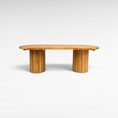 Chora Barefoot Luxury Living oval suar wood dining table with sculptural cylindrical bases and natural grain patterns.