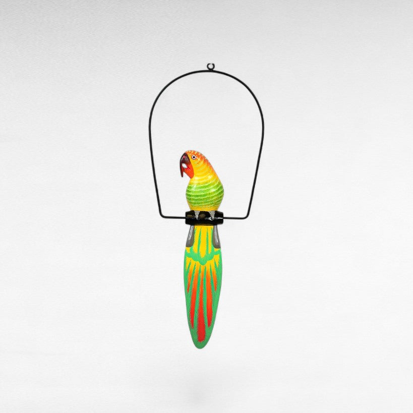 Chora Barefoot Luxury Living colorful wooden parrot decoration with yellow, green, and orange accents hanging from a black metal stand.