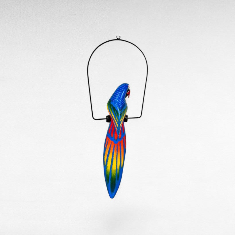 Chora Barefoot Luxury Living blue, yellow, and red painted parrot decoration hanging from a black metal stand.
