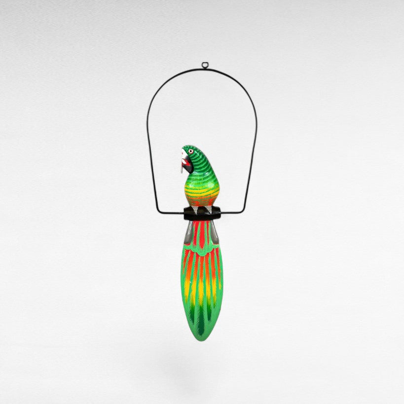 Chora Barefoot Luxury Living green and red painted wooden parrot decoration with yellow accents, hanging from a black metal frame.