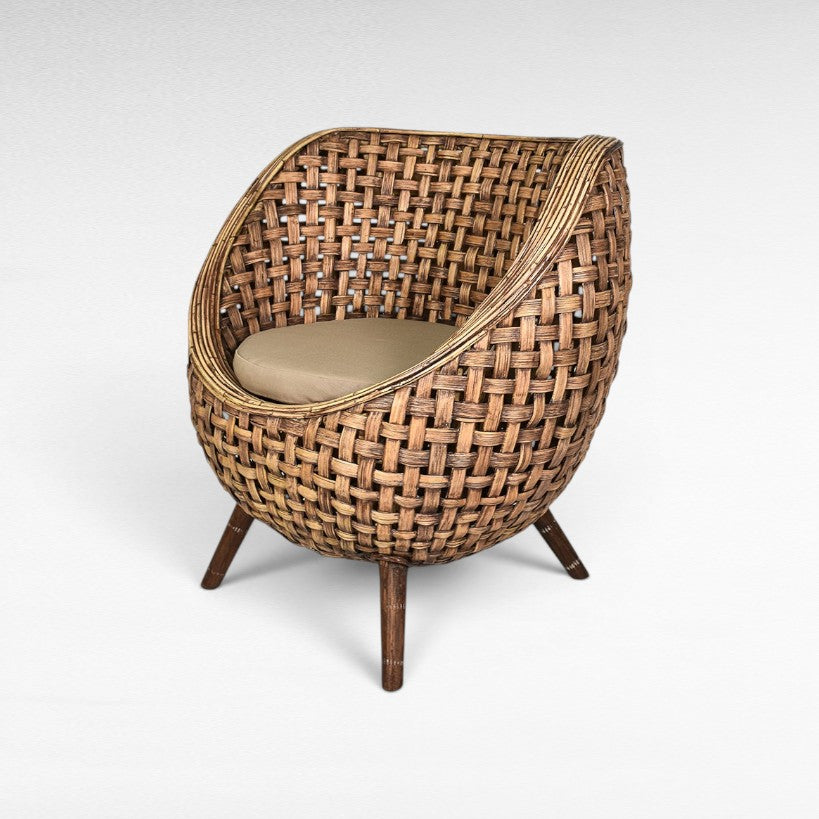 Chora Barefoot Luxury Living round rattan accent chair with tan cushion and wooden legs.