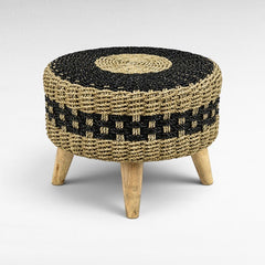 Chora Barefoot Luxury Living round stool with a black and natural hand-braided synthetic rattan seat and teak wood legs.