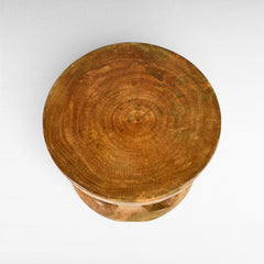Chora Barefoot Luxury Living round wooden side table with carved holes and curved base. Natural wood grain.