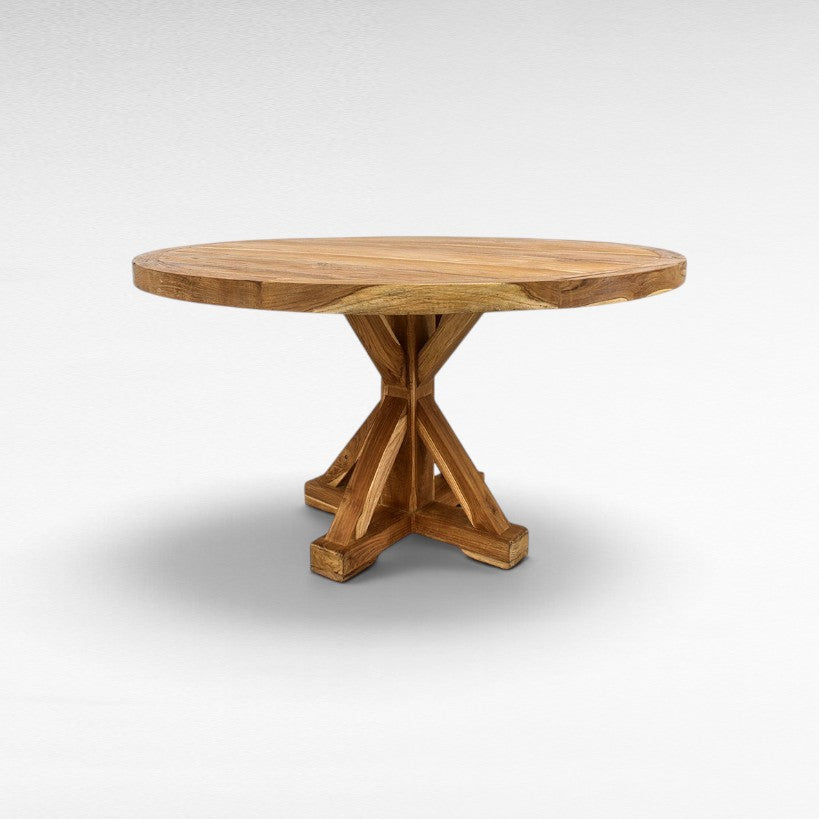 Chora Barefoot Luxury Living round wooden dining table with a sturdy cross-base design in a natural oak finish.