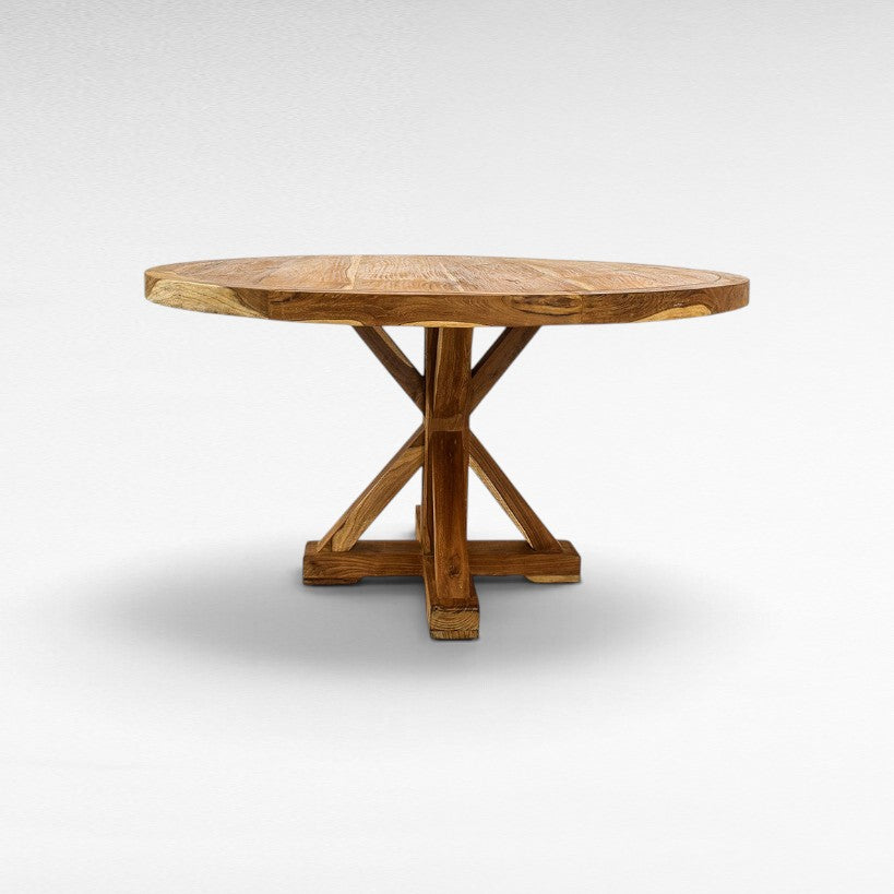 Chora Barefoot Luxury Living round wooden dining table with a sturdy cross-base design and natural grain finish.