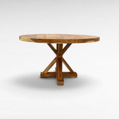 Chora Barefoot Luxury Living round wooden dining table with a sturdy cross-base design and natural grain finish.