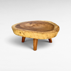 Chora Barefoot Luxury Living round suar wood coffee table with a thick slab top and three angled wooden legs.