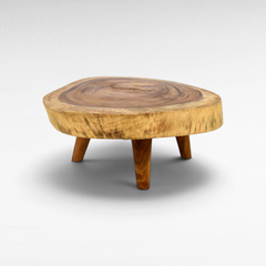 Chora Barefoot Luxury Living round suar wood coffee table with natural slab top and three angled wooden legs.