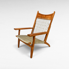 Chora Barefoot Luxury Living teak wood armchair with a woven synthetic raffia seat and decorative knotted backrest.