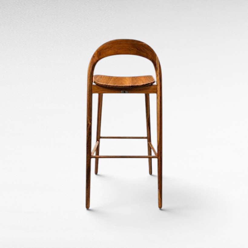 Chora Barefoot Luxury Living teak wood bar stool with a curved backrest and contoured seat in a natural wood finish.