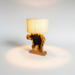 Chora Barefoot Luxury Living teak wood and black resin table lamp with natural wood grain and a beige linen shade.