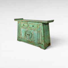 Chora Barefoot Luxury Living distressed teal wooden buffet with two drawers and carved circular motif on doors.