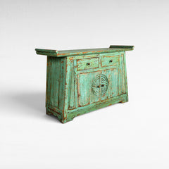 Chora Barefoot Luxury Living distressed teal wooden buffet with two drawers and carved circular motif on doors.