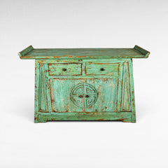 Chora Barefoot Luxury Living distressed teal wooden cabinet with two drawers and double doors featuring a carved circular motif.