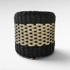 Chora Barefoot Luxury Living cylindrical stool made of woven black and natural grass rope with a textured pattern.