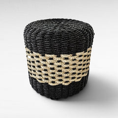 Chora Barefoot Luxury Living round stool featuring a black and natural woven grass pattern on a sturdy wood frame.
