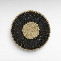 Chora Barefoot Luxury Living round woven stool with a black and natural hand-braided rattan seat, top view.