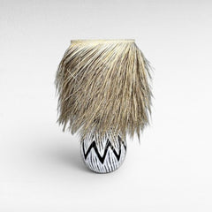 Chora Barefoot Luxury Living black and white patterned wood table lamp with natural raffia fringe shade.