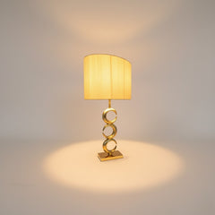 Chora Barefoot Luxury Living gold metal table lamp with a pleated cream shade and a stacked ring design on the base.