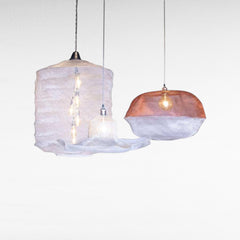 Chora Barefoot Luxury Living handwoven metal wire pendant lights in cloud shapes, one copper and white, one white with multiple bulbs.